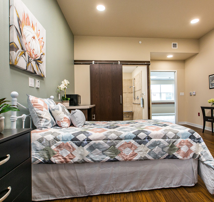 Hawkeye Care Center bedroom with a twin bed, and sliding door showing a part of the bathroom