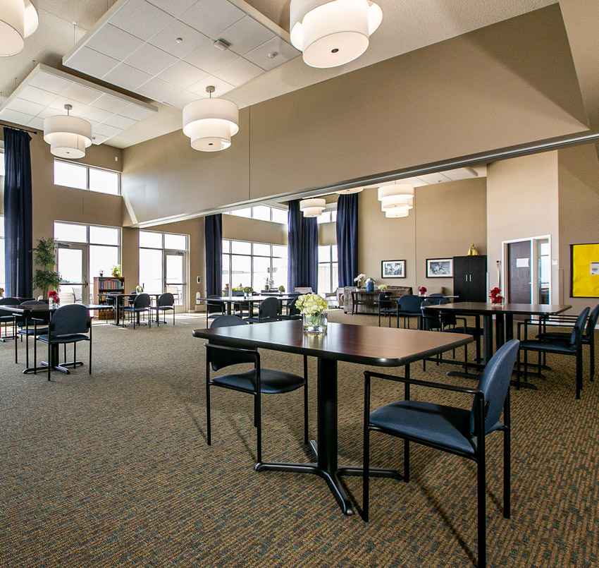 Hawkeye care center sitting area, with small rectangle tables each with two chairs spread across a large, open area.